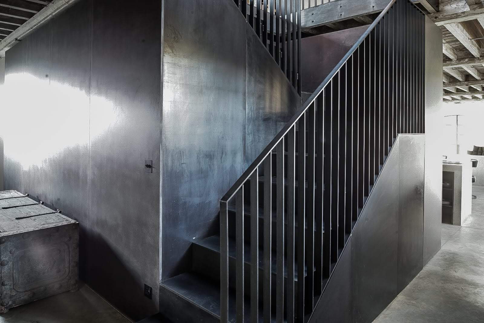 Blackened steel staircase with balustrade and matching wall cladding