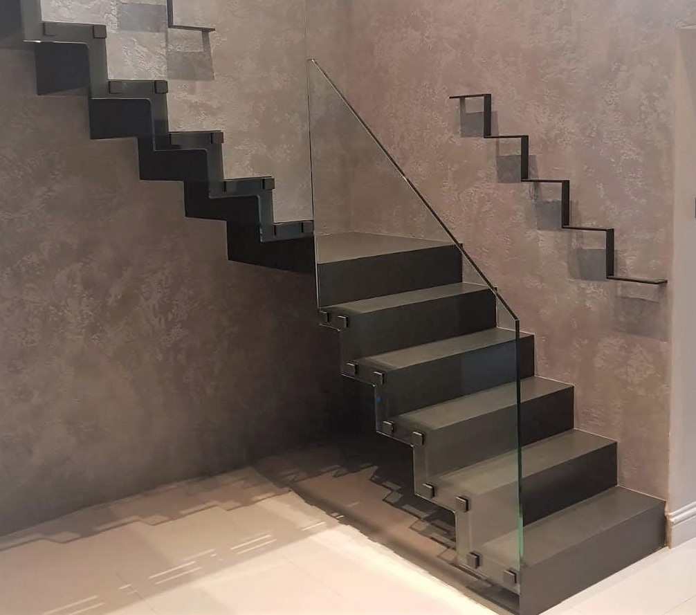 A cantilever staircase with a frameless glass balustrade and zigzag handrail