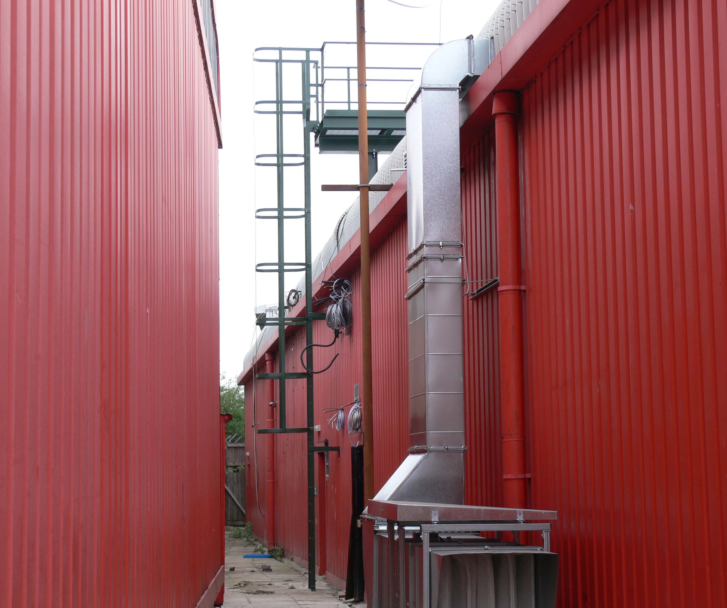A steel painted cat ladder with platform leading to roof access
