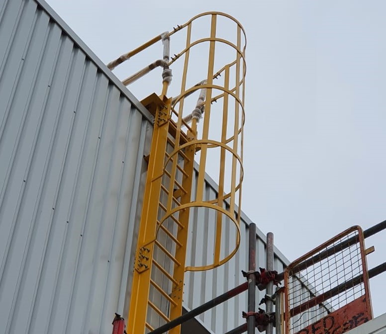 A steel yellow cat ladder with platform leading to roof access