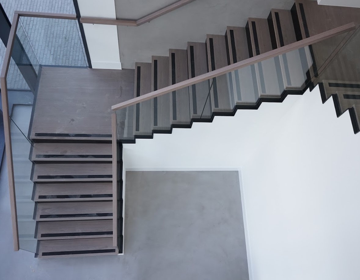 wooden handrail covered glass balustrade surrounding large staircase