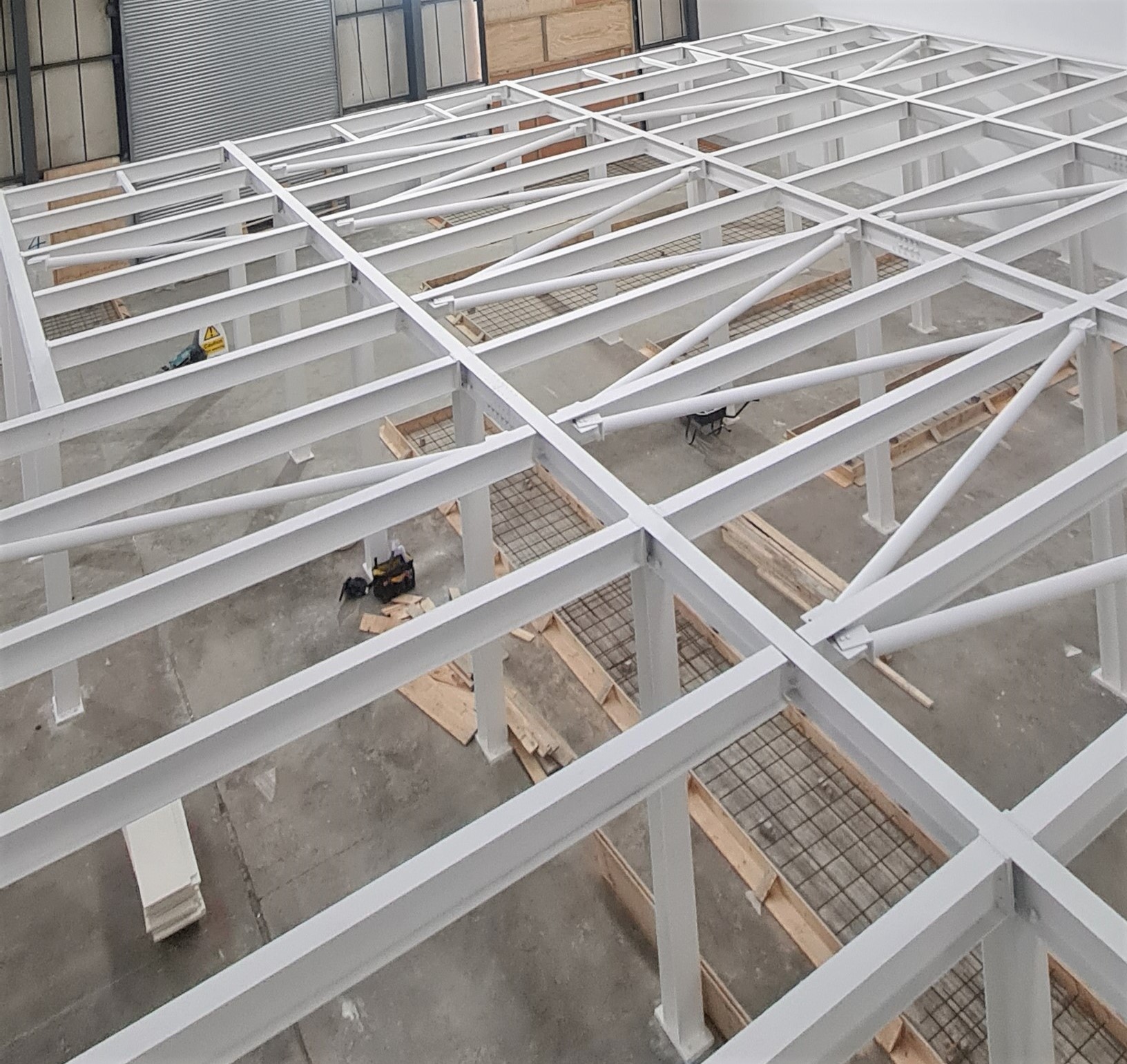 A white steel frame mezzanine assembled inside a large building.