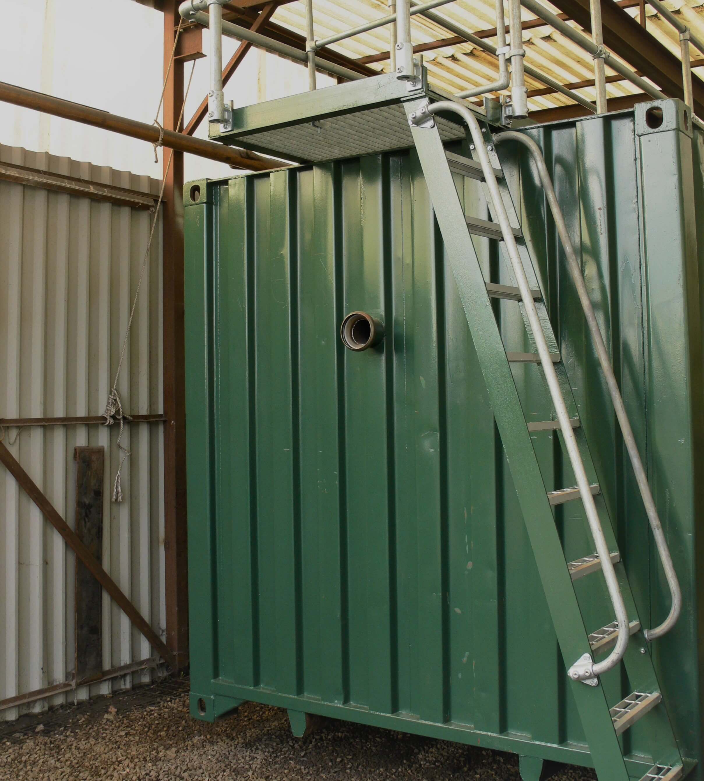A modified green container with a ladder and platform, also with ventilation hole