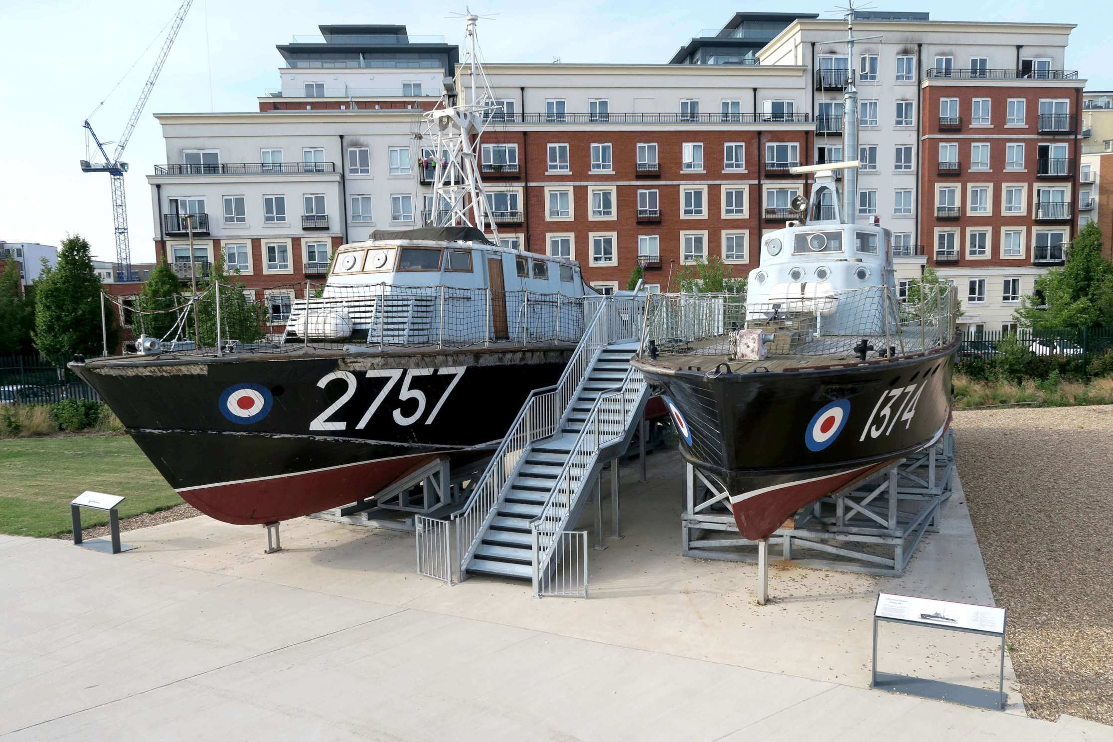 Two preserved RAF boats on stands, connected by a prominent central metal staircase/walkway for viewing.